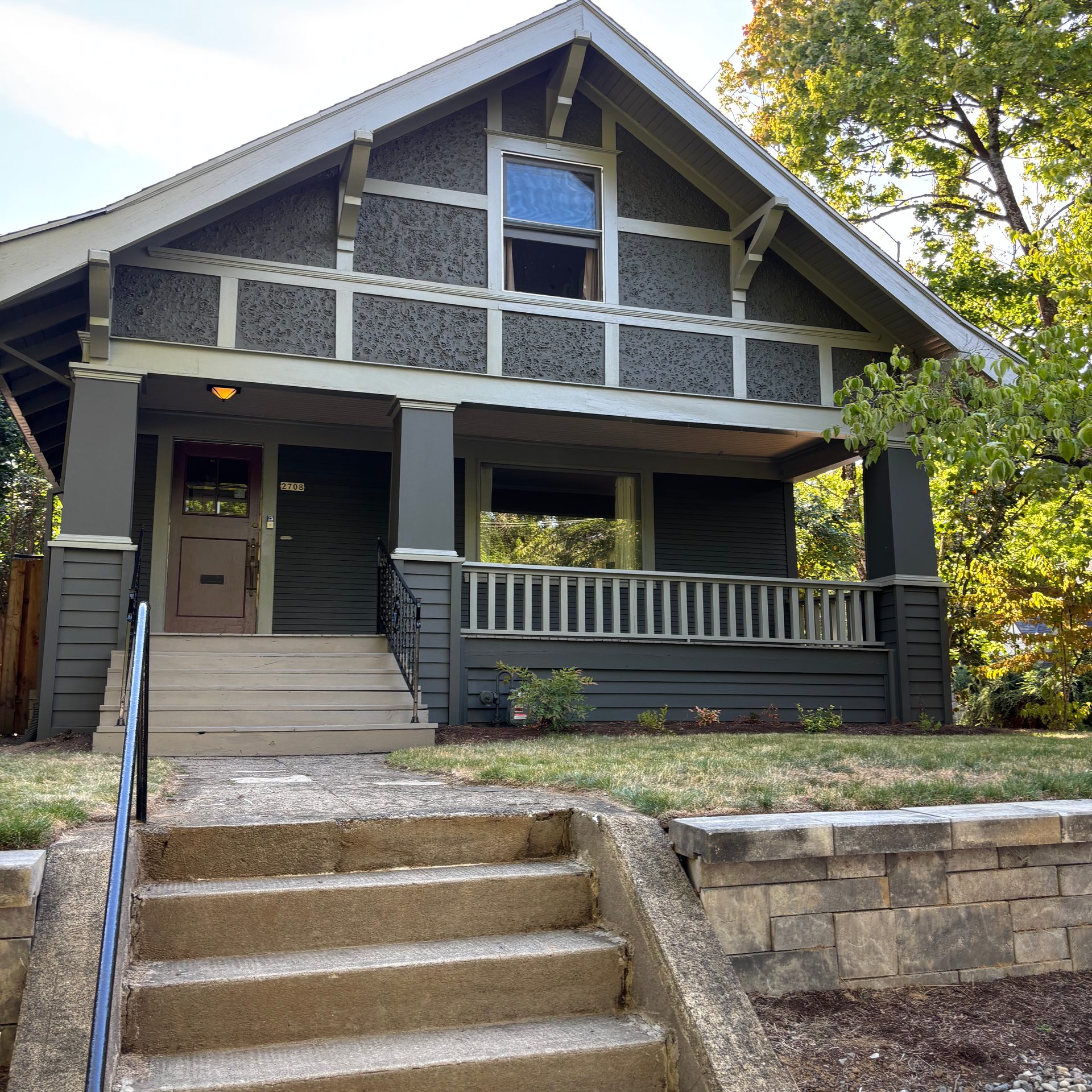 Olive and gray Craftsman with stone retaining wall