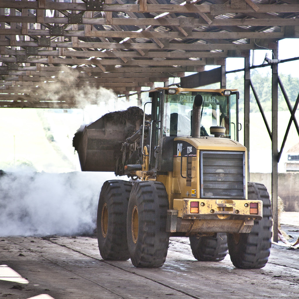 Cat loader moving steaming compost inside the on-site compost barn